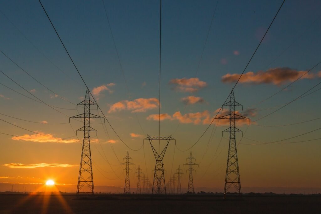 High-voltage transmission towers silhouetted against a sunset sky