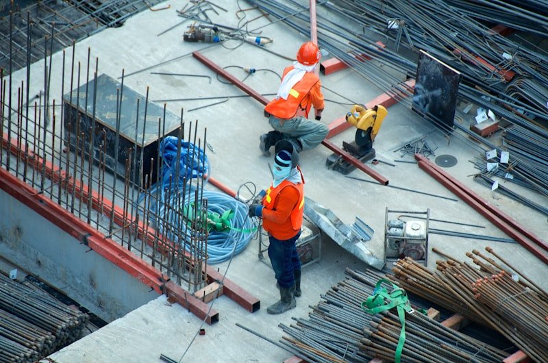 Construction workers in safety vests tying steel rebar on a building site