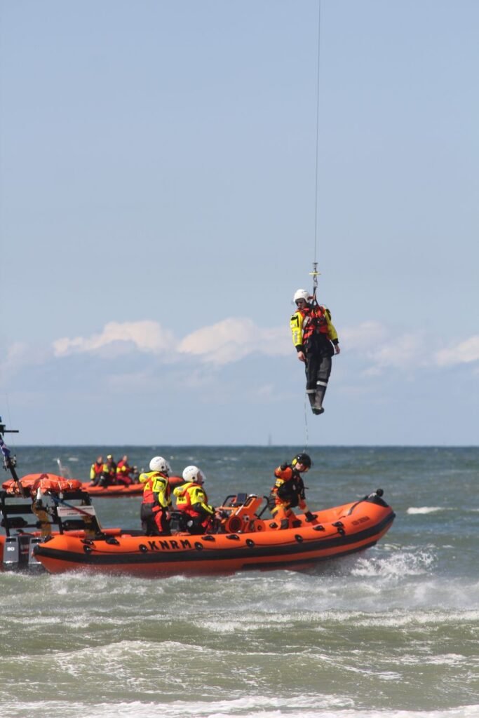 Nepal flood recovery and reconstruction: a water rescue team in rescue crafts and a man lifted on a line over the water