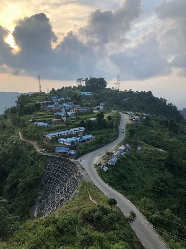 Mechi Highway Ilam upgrade: aerial view of a winding hill road through a village on a mountain in Nepal