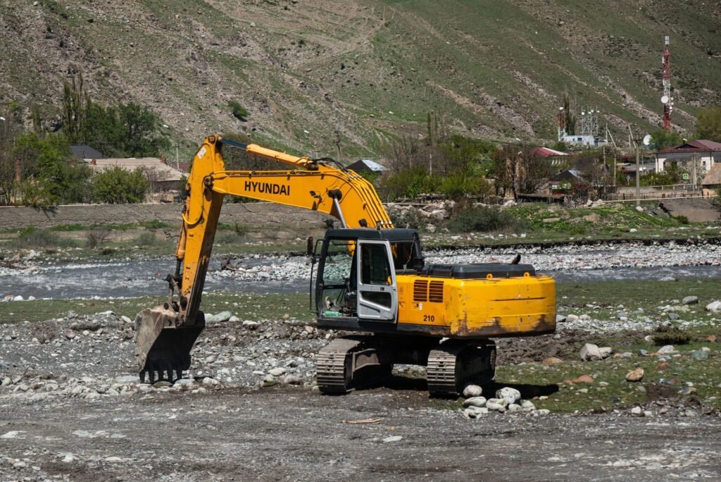 Maldhunga bridge geobags: excavator working on rocky terrain near a river at a bridge foundation site in rural Nepal